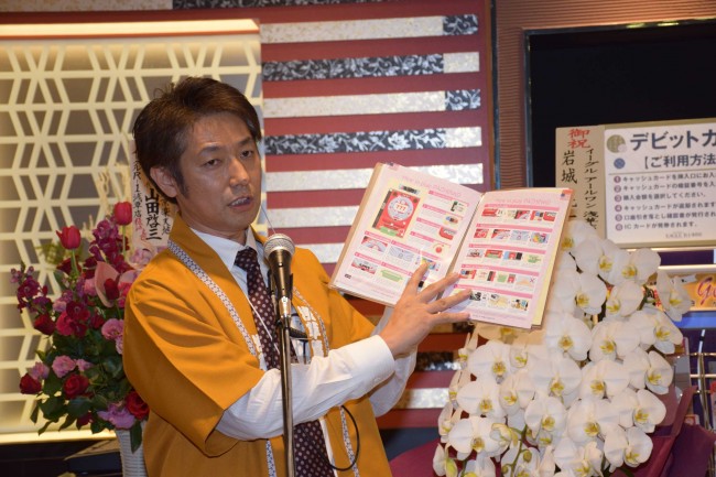 イーグル浅草店02　3カ国語で書かれた遊技ガイドを紹介する牧田店長